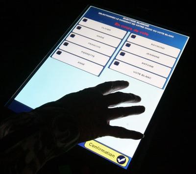 A Hand Touches The Screen Of A Voting Machine